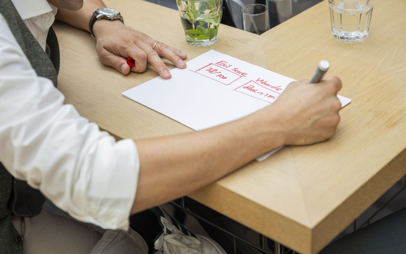 Adviseur berekent met de hand de EBITDA op papier tijdens een adviesgesprek